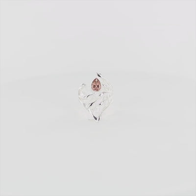 Bague en argent massif présentant un design sculptural évoquant un entrelacs une feuille stylisée, alternant entre surfaces lisses polies et zones texturées satinées. En son centre est sertie une tourmaline rose taille poire, lumineuse, aux reflets délicats. Bague réalisée en taille 54. Bijoux unique, éthique et durable présenté dans un coffret de notre marque, prêt à offrir. Livraison offerte, certificat d'authenticité, service client.