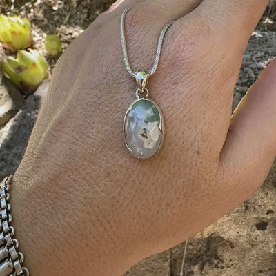 Pendentif ovale en argent massif, serti d'un cabochon de calcédoine de couleur blanche verte. Pierre de qualité translucide comportant des inclusions paysages blanches. Bijoux unique par Orcha Jewelry