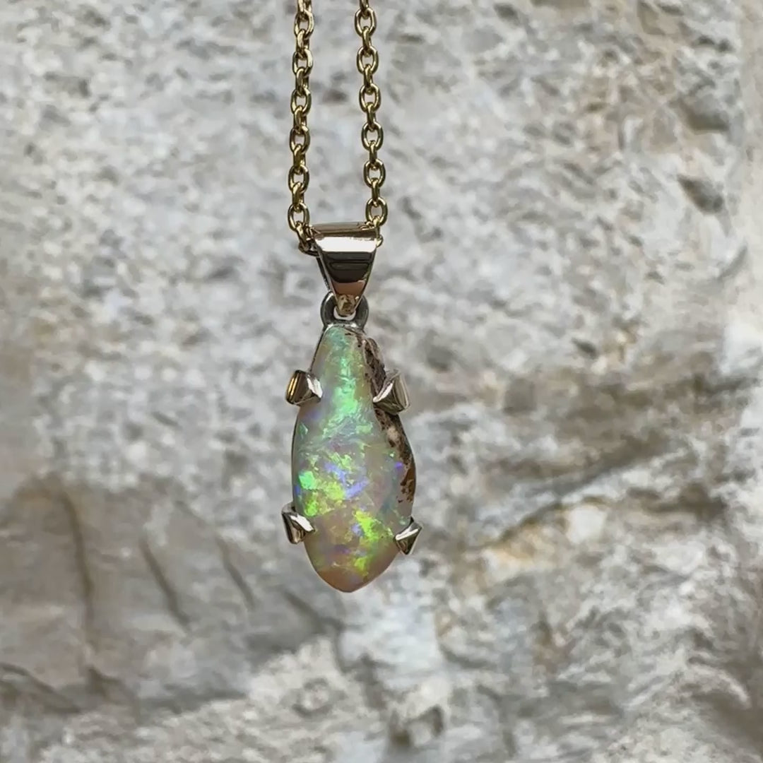 Pendentif pour femme en or 9k et argent massif 925 serti d'une opale cristal aux feux étoilés multicolores à dominantes vert et jaune. Cabochon de 3,3 carats de forme libre et de qualité translucide avec présence de roche mère. Bijou unique réalisé par Orchajewelry