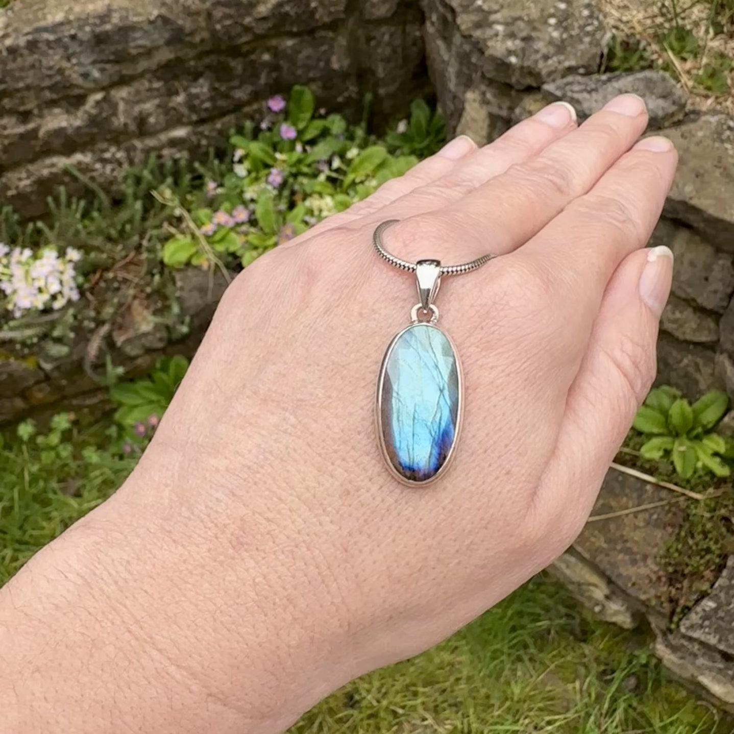 Pendentif pour femme en argent massif sertie d'une labradorite aux reflets bleus clairs selon la lumière. Pierre facettée naturelle translucide présentant des inclusions fréquents sur ce type de pierre. Bijoux unique, éthique et durable présenté dans un coffret de notre marque, prêt à offrir. Livraison offerte, certificat d'authenticité, service client.