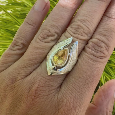vidéo d"'une Grande bague contemporaine pour femme en argent massif sertie d'une Citrine. Pierre facettée en forme de goutte de qualité transparente, propre à l'oeil. Pierre naturelle de couleur jaune or lumineux. Bijoux unique, éthique et durable présenté dans un coffret de notre marque, prêt à offrir. Livraison offerte, certificat d'authenticité, service client.