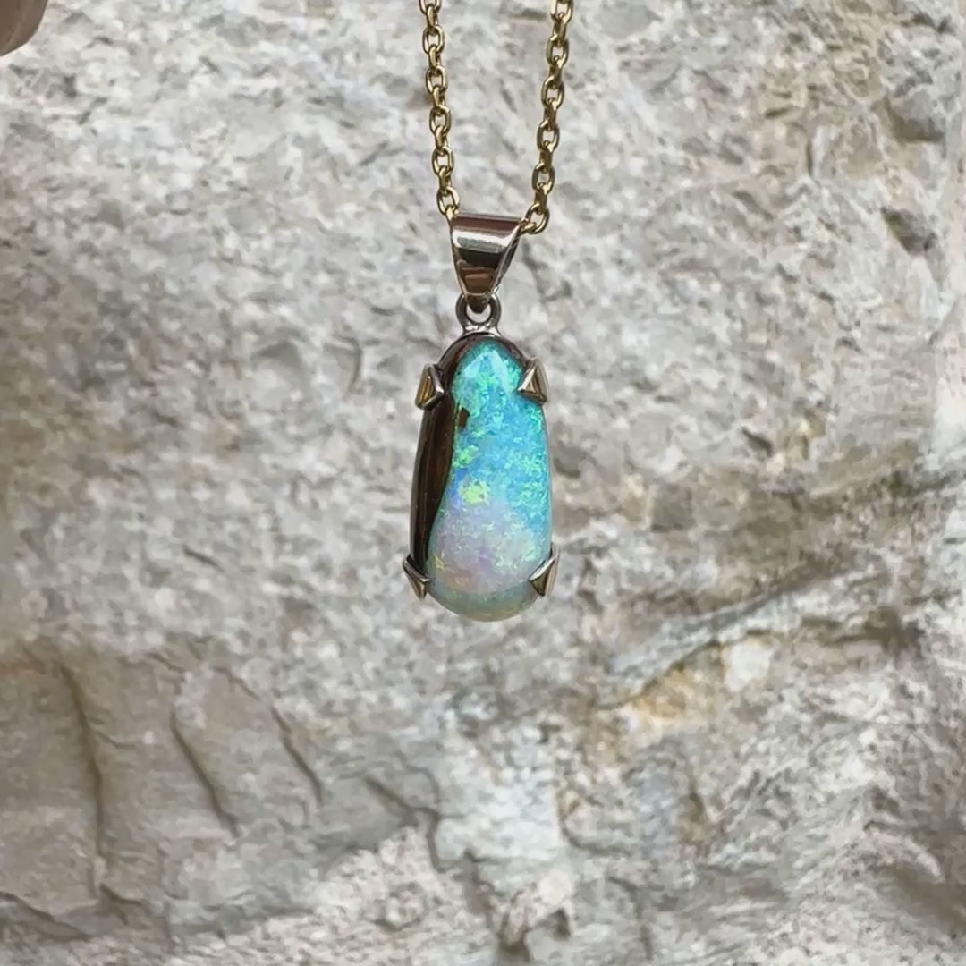 Pendentif pour femme en or 9k et argent massif serti d'une opale boulder cristal aux feux étoilés multicolores à dominantes bleu turquoise. Cabochon de 7 carat taillé en forme de goutte de qualité translucide. Opale massive australienne. Bijou unique réalisé par Orchajewelry