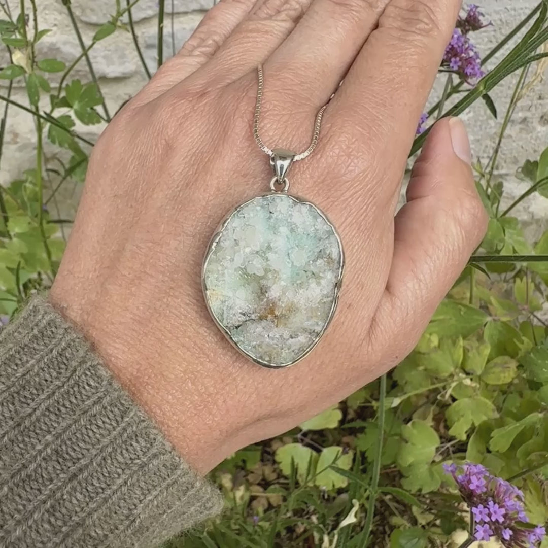 Pendentif en argent massif serti d'un magnifique gemsilica druze: chrysocolle silicifiée recouverte de fins cristaux de quartz scintillant. Pierre de qualité opaque brute de forme ovale. Pierre naturelle originaire du Mexique de couleur verte bleutée claire.
