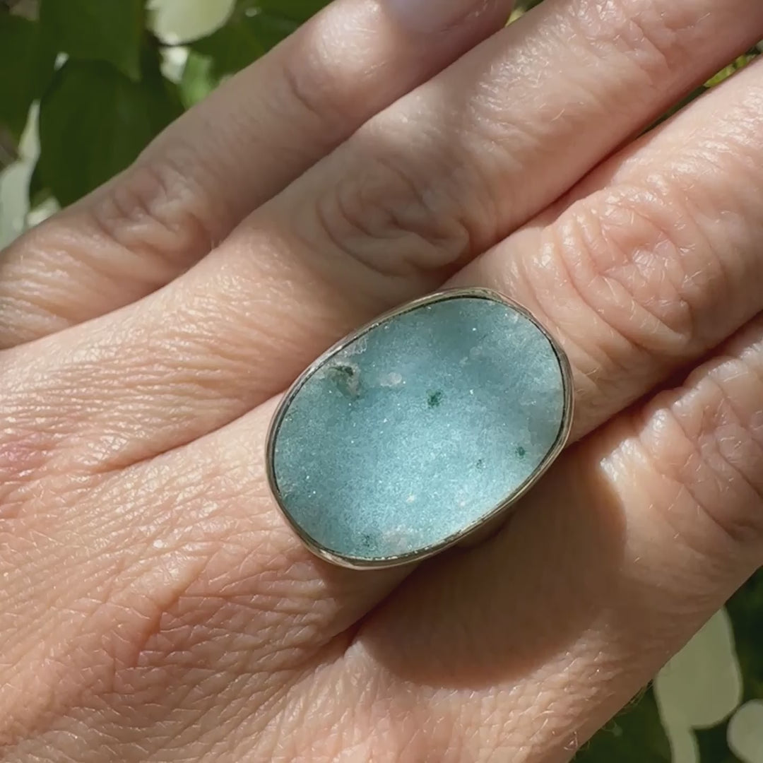 Bague pour femme en argent massif sertie d'un magnifique gemsilica druzy: chrysocale silicifiée recouverte de fins cristaux de quartz scintillants. Pierre de qualité opaque taillée en tranche de forme ovale. Pierre naturelle originaire de République dominicaine du Congo de couleur bleu clair turquoise. Bague réalisée en taille 58,5. Bijoux unique, éthique et durable présenté dans un coffret de notre marque, prêt à offrir. Livraison offerte, certificat d'authenticité, service client.
