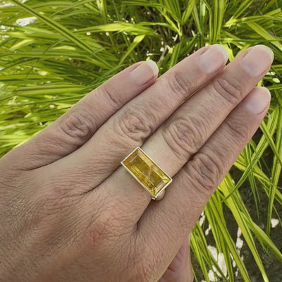 Vidéo d'une bague cocktail pour femme en argent massif sertie d'une Héliodore. Pierre facettée de forme rectangulaire de qualité transparente avec inclusions naturelles. Pierre de couleur jaune soleil intense. Bague réalisée en taille 60.5. Bijoux unique, éthique et durable présenté dans un coffret de notre marque, prêt à offrir. Livraison offerte, certificat d'authenticité, service client.