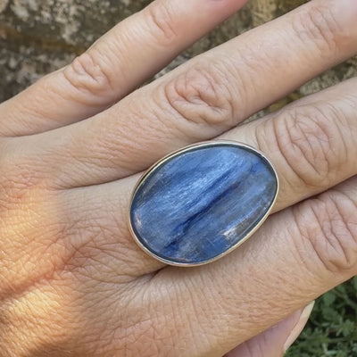 Bague pour femme en argent massif sertie d'un cabochon de cyanite de couleur bleu jean irisée. Pierre translucide à inclusions. Bijou unique réalisée en taille 56 par Orcha Jewelry