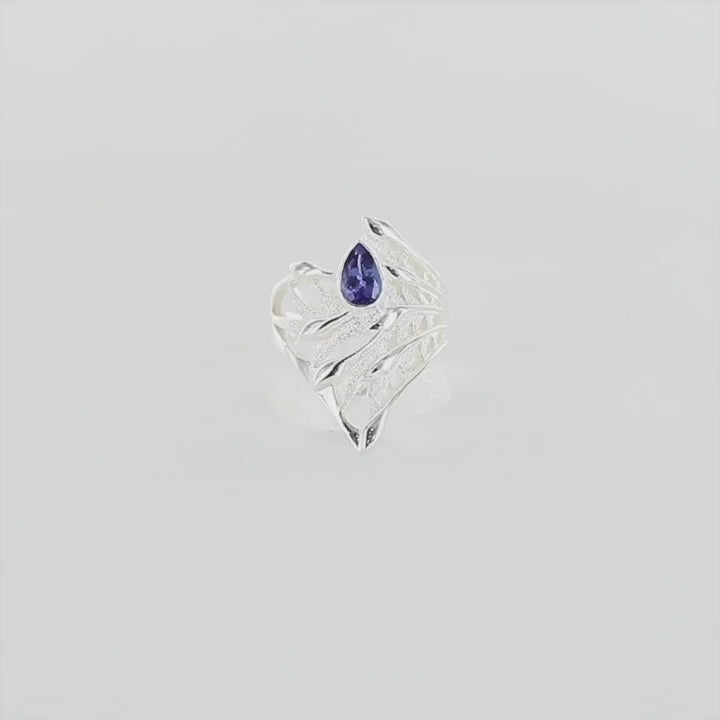 Vidéo a 360 degré d'une grande bague florale pour femme en argent massif sertie d'une Tanzanite. Pierre facettée en forme de goutte, pierre chauffée à la couleur bleue lavande intense. Pierre transparente et propre à l'oeil. Taille 58. Bijoux unique, éthique et durable présenté dans un coffret de notre marque, prêt à offrir. Livraison offerte, certificat d'authenticité, service client.
