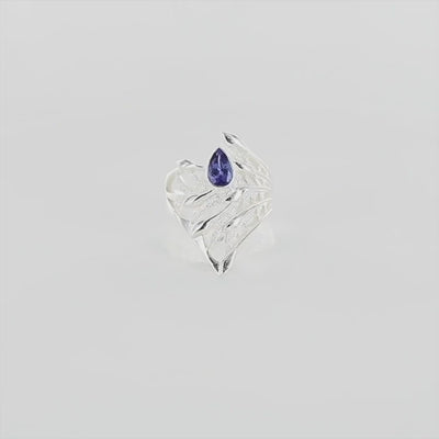 Vidéo a 360 degré d'une grande bague florale pour femme en argent massif sertie d'une Tanzanite. Pierre facettée en forme de goutte, pierre chauffée à la couleur bleue lavande intense. Pierre transparente et propre à l'oeil. Taille 58. Bijoux unique, éthique et durable présenté dans un coffret de notre marque, prêt à offrir. Livraison offerte, certificat d'authenticité, service client.
