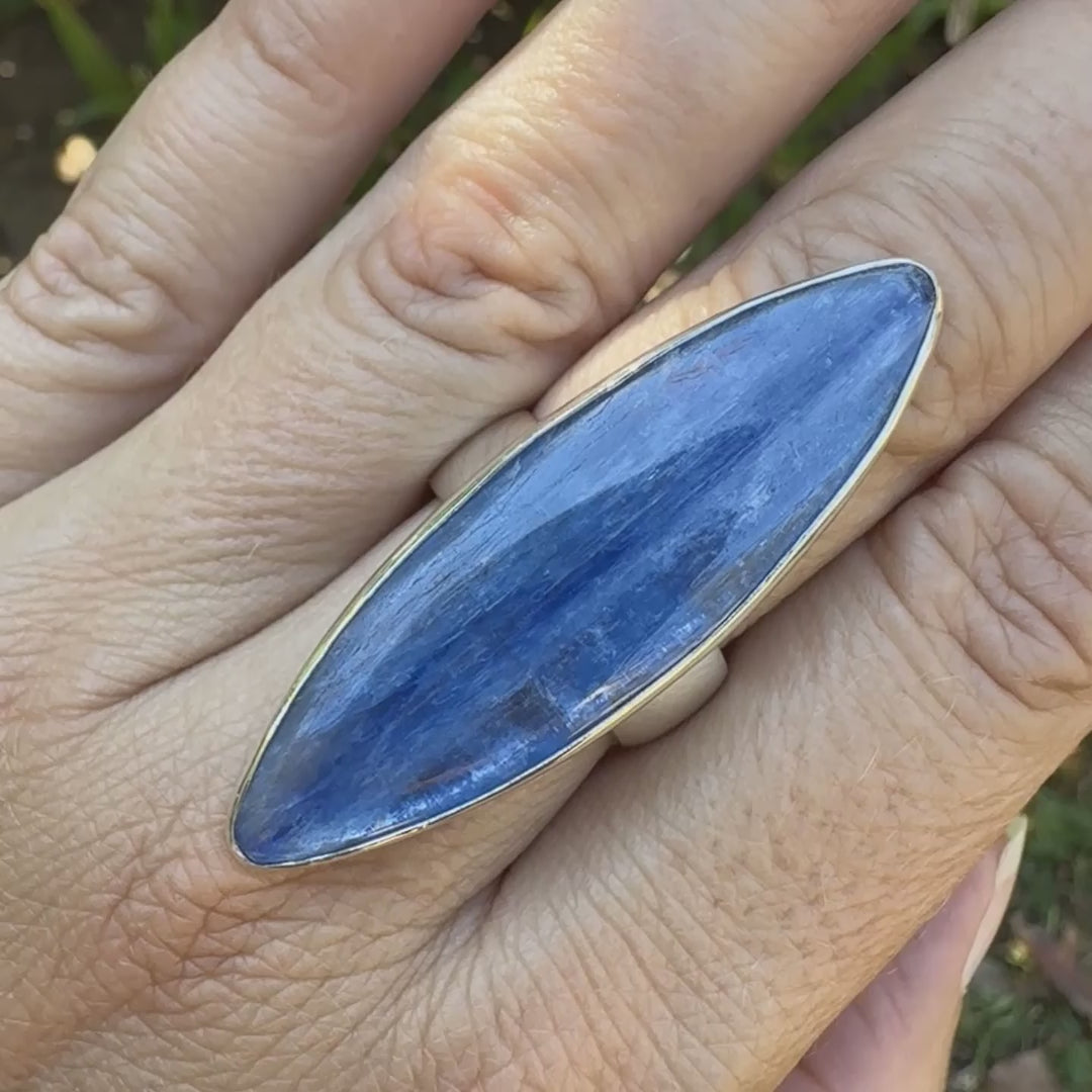Bague marquise pour femme en argent massif sertie d'un cabochon de cyanite de couleur bleu jean nacré. Pierre translucide à inclusions. Bijou unique réalisée en taille 58 par Orchajewelry