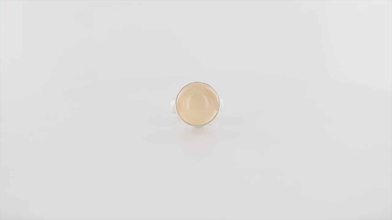 Bague contemporaine en argent massif pour femme sertie d'une pierre de lune orange. Pierre cabochon de forme ronde. Pierre transparente naturelle de couleur orange à  chatoyance et effet satiné. Bague réalisée en taille 56. Bijoux unique, éthique et durable présenté dans un coffret de notre marque, prêt à offrir. Livraison offerte, certificat d'authenticité, service client.