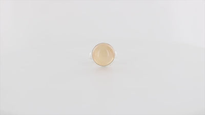 Bague contemporaine en argent massif pour femme sertie d'une pierre de lune orange. Pierre cabochon de forme ronde. Pierre transparente naturelle de couleur orange à  chatoyance et effet satiné. Bague réalisée en taille 56. Bijoux unique, éthique et durable présenté dans un coffret de notre marque, prêt à offrir. Livraison offerte, certificat d'authenticité, service client.