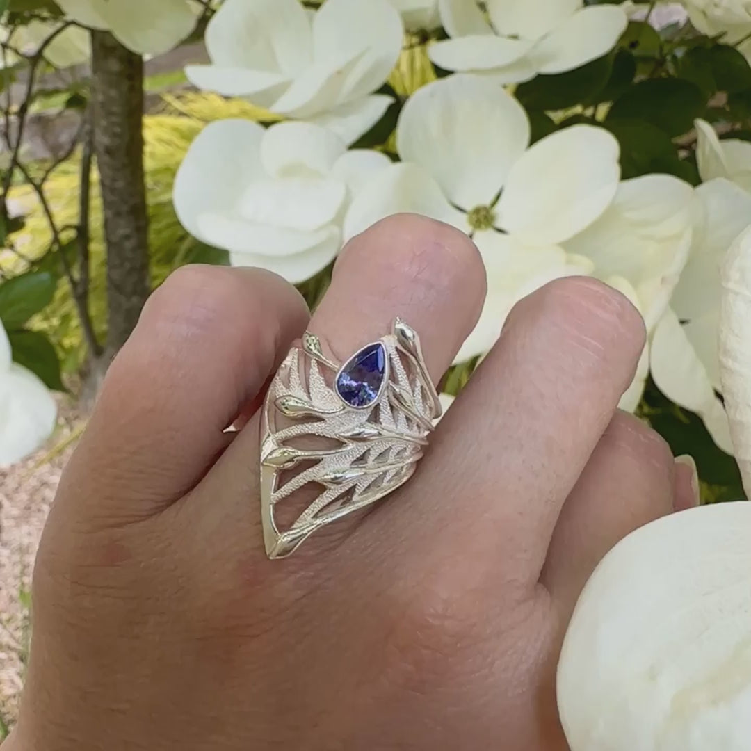 vidéo d'une grande Bague pour femme, feuillage tropicale travaillé en filigrane en argent massif, sertie d'une Tanzanite bleu lavande. Pierre facettée en forme de goutte. Pierre lumineuse et propre à l'oeil. Bijoux unique, éthique et durable présenté dans un coffret de notre marque, prêt à offrir. Livraison offerte, certificat d'authenticité, service client.