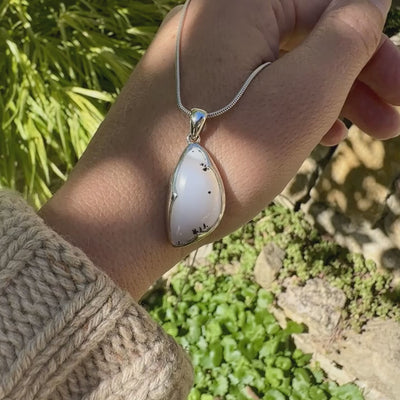 Pendentif pour femme en argent massif sertie d'un cabochon en forme d'aile d'agate dendritique de couleur blanc pur et noir. Pierre opaque à translucide à inclusions paysages de dendrites de manganèse noires contrastées. Bijou unique réalisé par Orchajewelry