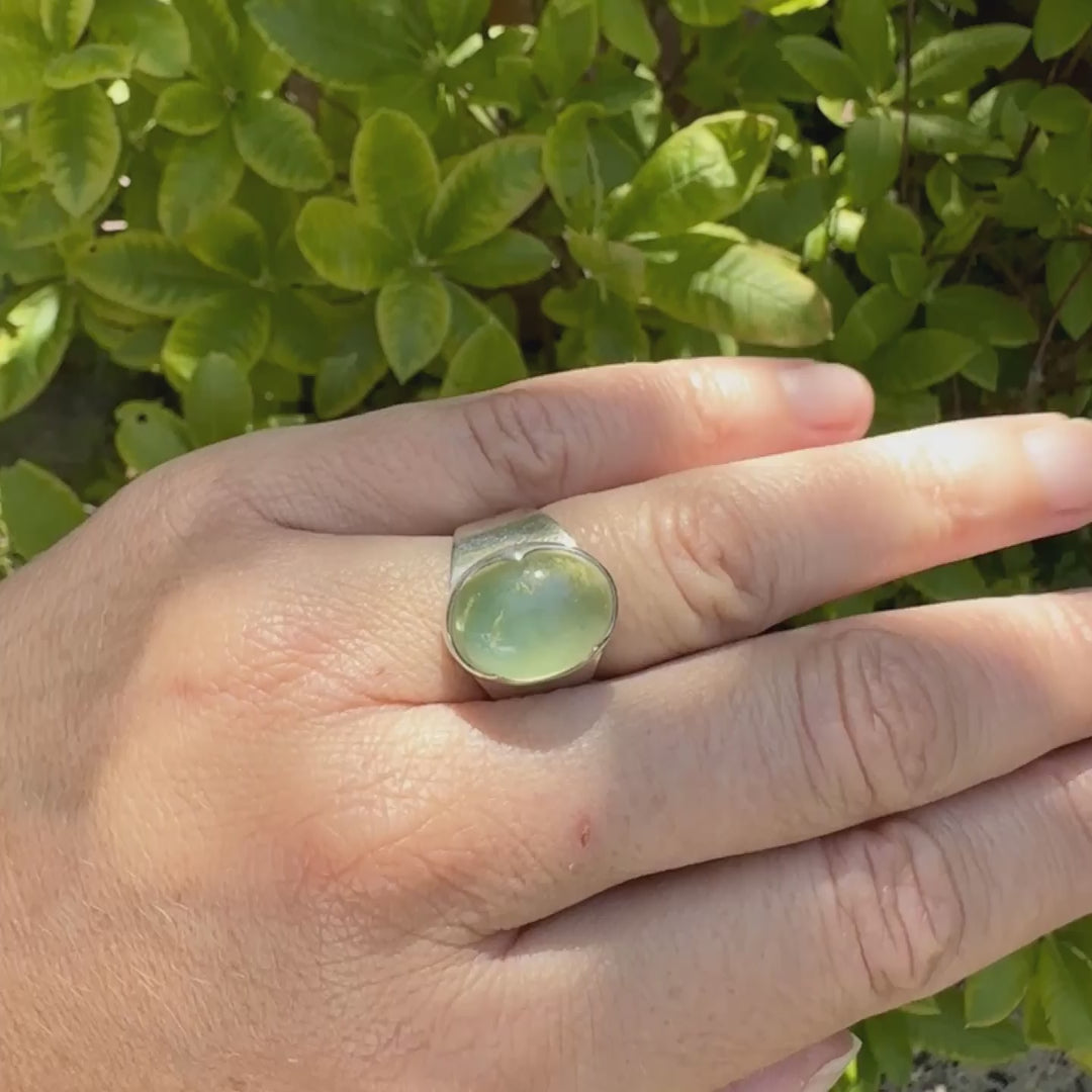 Bague pour femme en argent massif sertie d'une préhnite de couleur verte jaune clair. Pierre ovale taillée en cabochon. Pierre gemme de qualité transparente à inclusions. Bijoux unique réalisé en taille 52 par Orchajewelry.