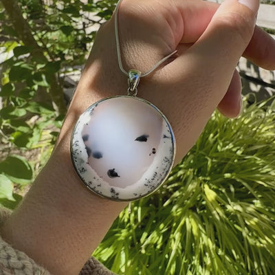 Pendentif pour femme en argent massif sertie d'un cabochon rond d'agate dendritique de couleur blanc pur et noir. Pierre opaque à translucide à inclusions paysages de dendrites de manganèse noires contrastées. Bijou unique réalisé par Orchajewelry