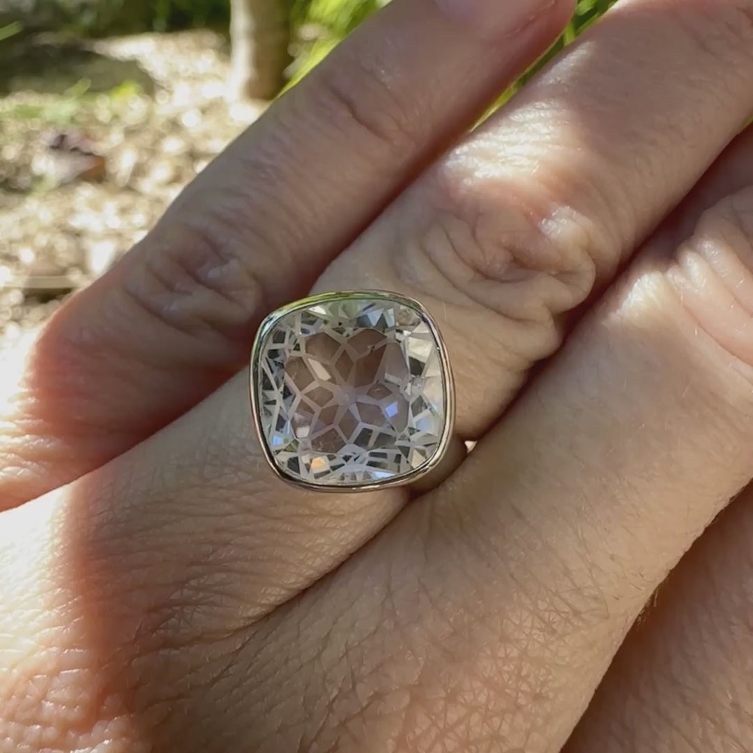 Bague cocktail pour femme en argent massif sertie d'un Cristal de roche gravé d'une fleur de vie. Pierre facettée de forme carrée de qualité transparente, propre à l'oeil. Pierre naturelle incolore et blanche sur les parties gravées. Bague réalisée en taille 52 ou 54. Bijoux unique, éthique et durable présenté dans un coffret de notre marque, prêt à offrir. Livraison offerte, certificat d'authenticité, service client.