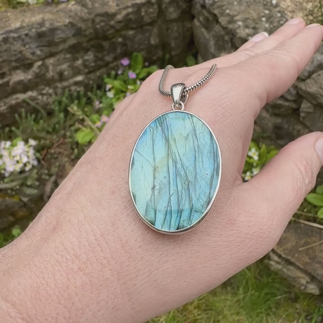 Pendentif ovale pour femme en argent massif serti d'une labradorite aux reflets bleus clairs, bleu vert selon la lumière. Pierre facettée naturelle translucide présentant des inclusions fréquents sur ce type de pierre. Bijoux unique, éthique et durable présenté dans un coffret de notre marque, prêt à offrir. Livraison offerte, certificat d'authenticité, service client.