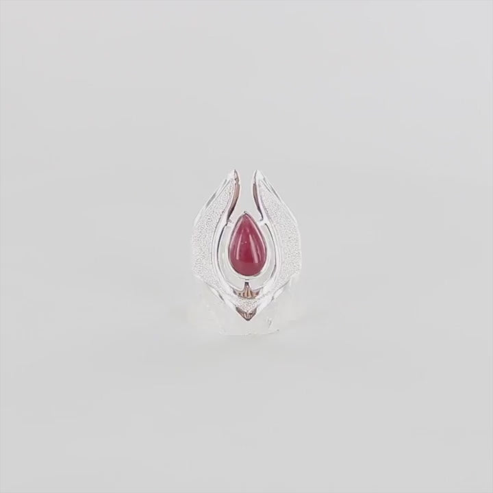 Video 360 degré d'une longue bague pour femme en argent massif sertie d'une Rhodonite. Pierre cabochon en forme de goutte, pierre naturelle de couleur rouge coquelicot. Pierre fine de qualité  opaque à translucide présentant des inclusions. Taille 54. Bijoux unique, éthique et durable présenté dans un coffret de notre marque, prêt à offrir. Livraison offerte, certificat d'authenticité, service client.