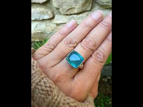 Bague cocktail pour femme en argent massif sertie d'une aigue marine taillée de 10 carats de couleur bleue gris foncé, pierre transparente avec inclusions. Pierre naturelle facettée de forme rectangulaire. Bijoux unique réalisée en taille 60,5 par Orchajewelry
