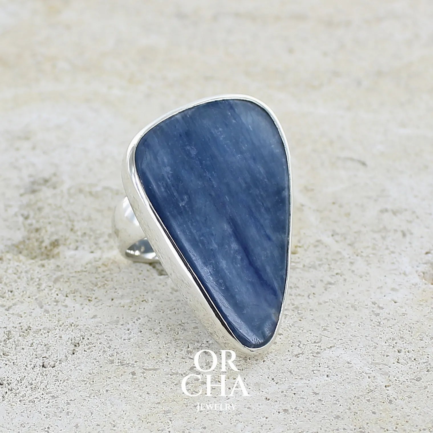 profil droit d'une Bague longue et imposante pour femme en argent massif, sertie d'un cabochon de cyanite de couleur bleu jean nacré. Pierre taillée en forme de triangle de qualité translucide. Bijou unique réalisée en taille 58 par Orchajewelry