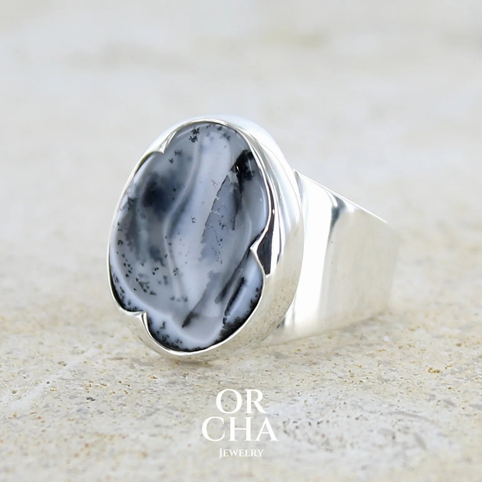 Profil d'une bague pour femme en argent massif sertie d'un cabochon ovale d'agate dendritique de couleur blanc pur et noir. Pierre opaque translucide à inclusions paysages de dendrites de manganèse noires contrastées. Bijou unique réalisée en taille 54 par Orchajewelry