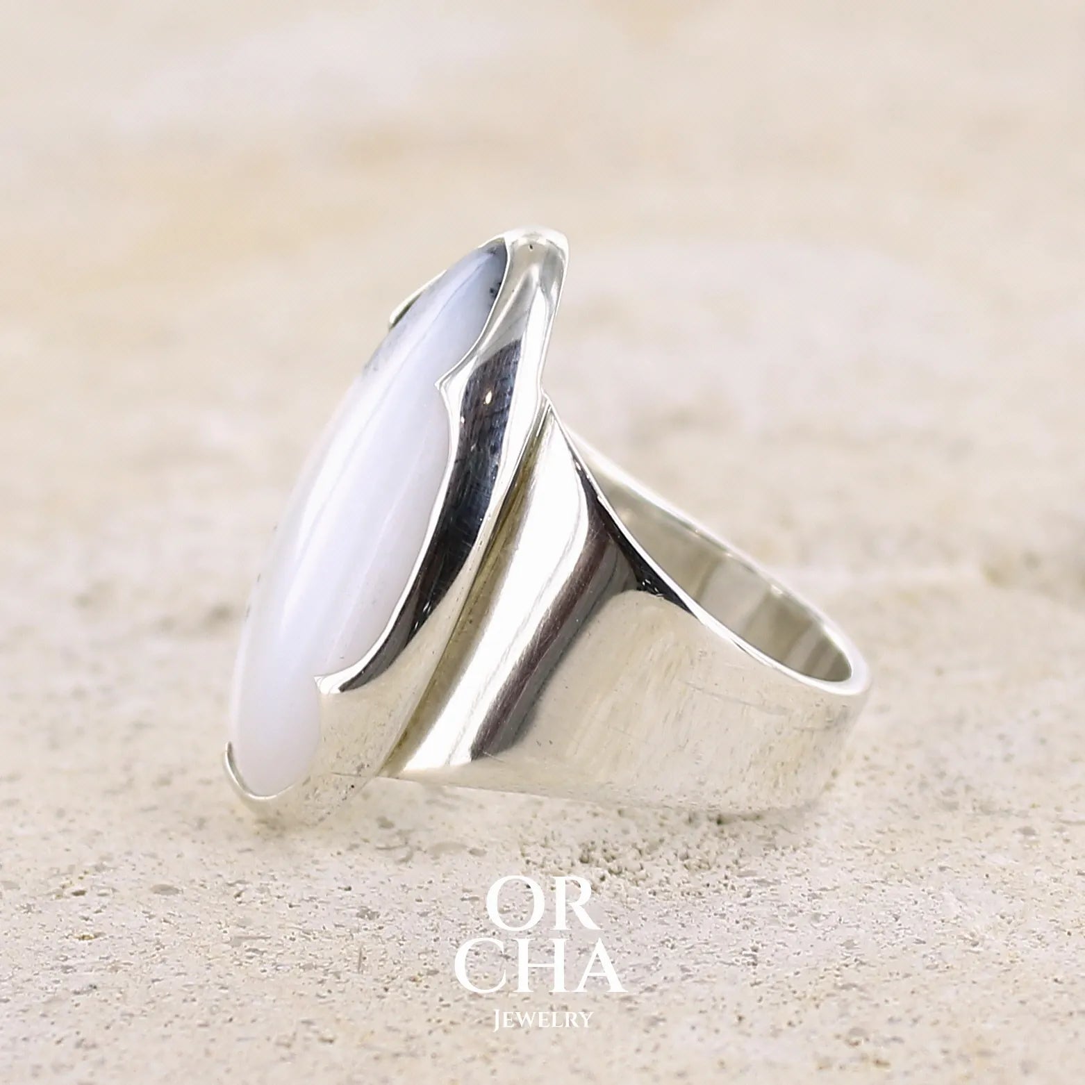 Profil d'une bague pour femme en argent massif sertie d'un cabochon d'agate dendritique de couleur blanche et noire. Pierre translucide à inclusions paysages de manganèse contrastées. Bijou unique réalisée en taille 58 par Orcha Jewelry