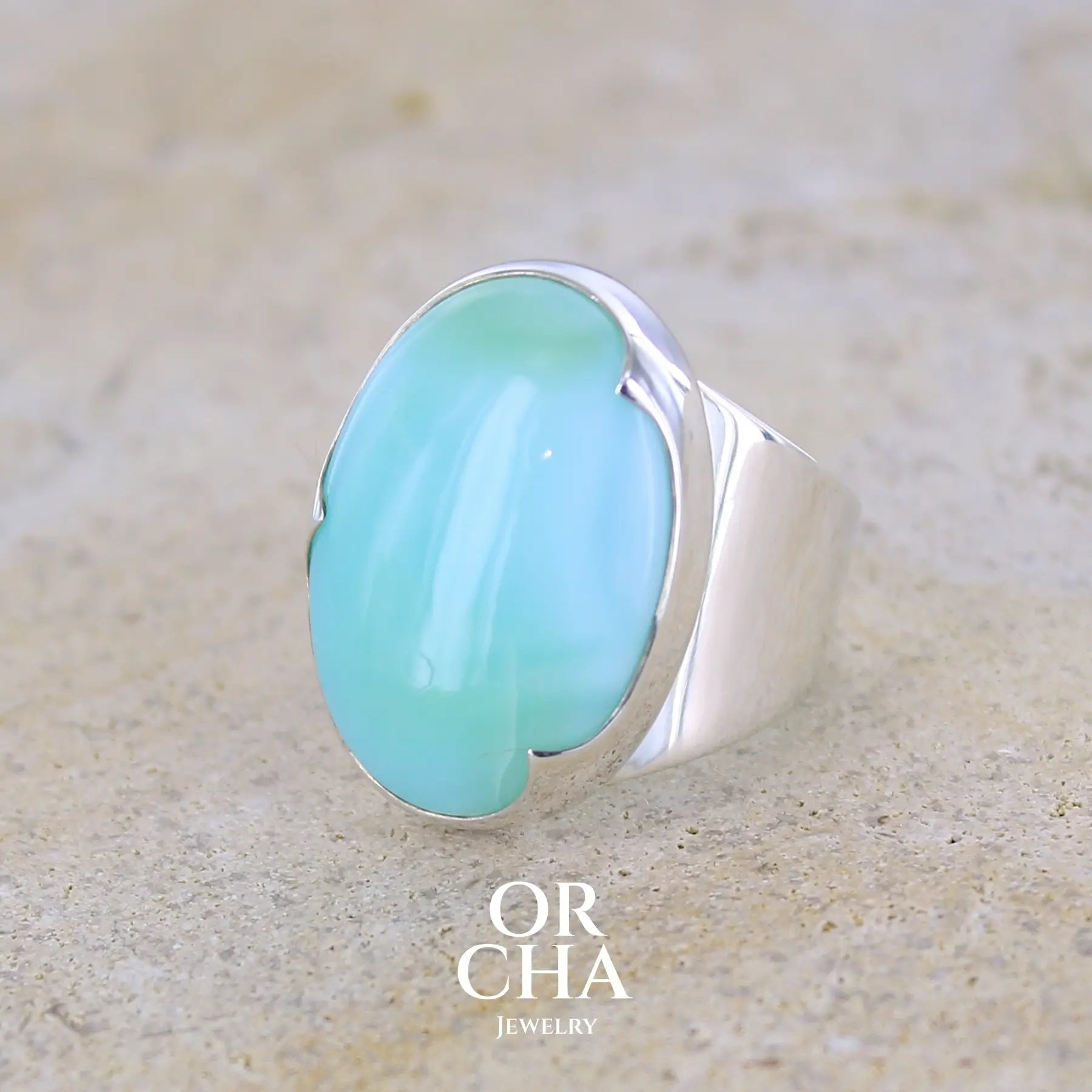 profil gauche d'une grande Bague pour femme en argent massif, sertie d'un cabochon d'opale bleue du Pérou. Pierre taillée de forme ovale. Pierre opaque. Taille 58,5. Bijoux unique, éthique et durable présenté dans un coffret de notre marque, prêt à offrir. Livraison offerte, certificat d'authenticité, service client.
