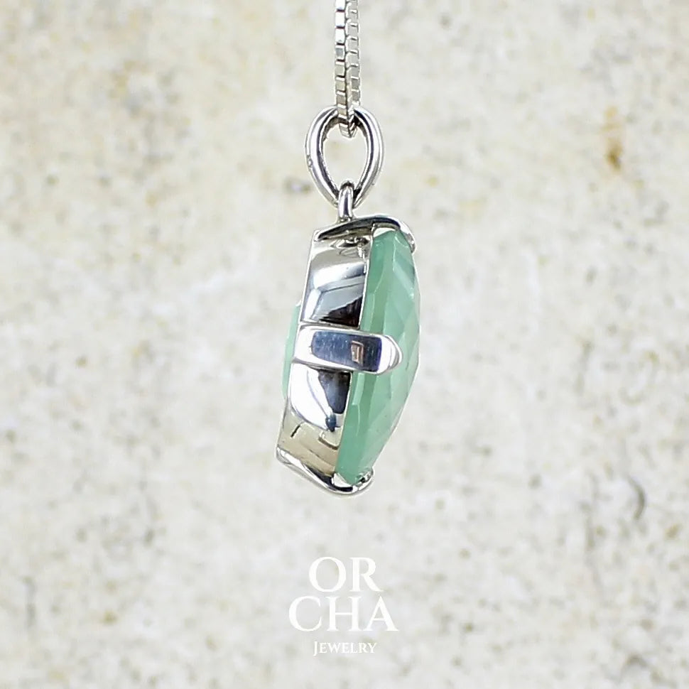 profil droit d'un Pendentif ovale en argent massif, serti d'un cabochon facetté de préhnite de couleur bleue verte. Pierre de qualité translucide comportant des inclusions. blanches. Bijoux unique par Orcha Jewelry