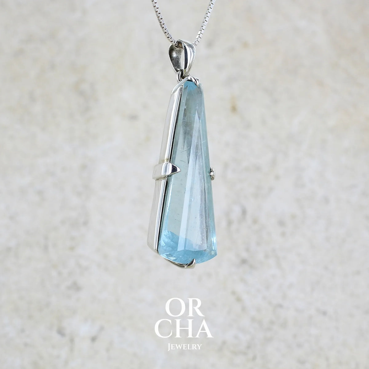 profil droit d'un Pendentif en argent massif sertie d'une aigue marine taillée de 32 carats de couleur bleu clair profond et lumineux, pierre transparente avec inclusions. Pierre naturelle facettée de forme triangulaire allongé. Bijoux unique réalisée par Orchajewelry