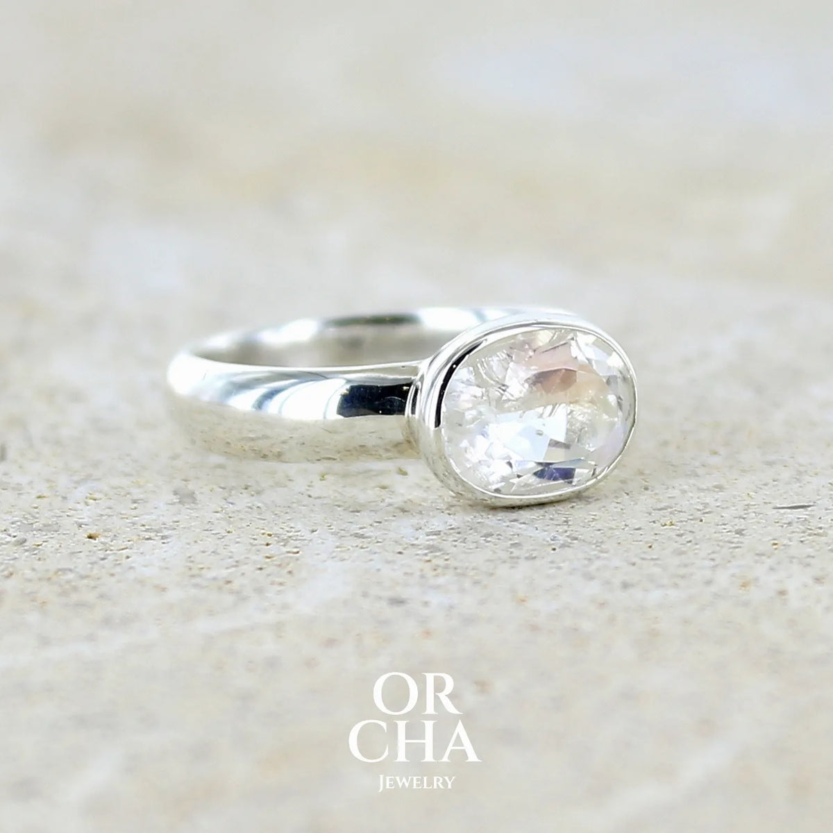 profil droit d'une bague cocktail pour femme en argent massif 925 sertie d'une pierre de lune de Madagascar taillée de 2,18 carats, pierre incolore aux reflets orangés et arc en ciel. Pierre transparente avec inclusions. Bijoux unique réalisé en taille 52 par Orcha Jewelry