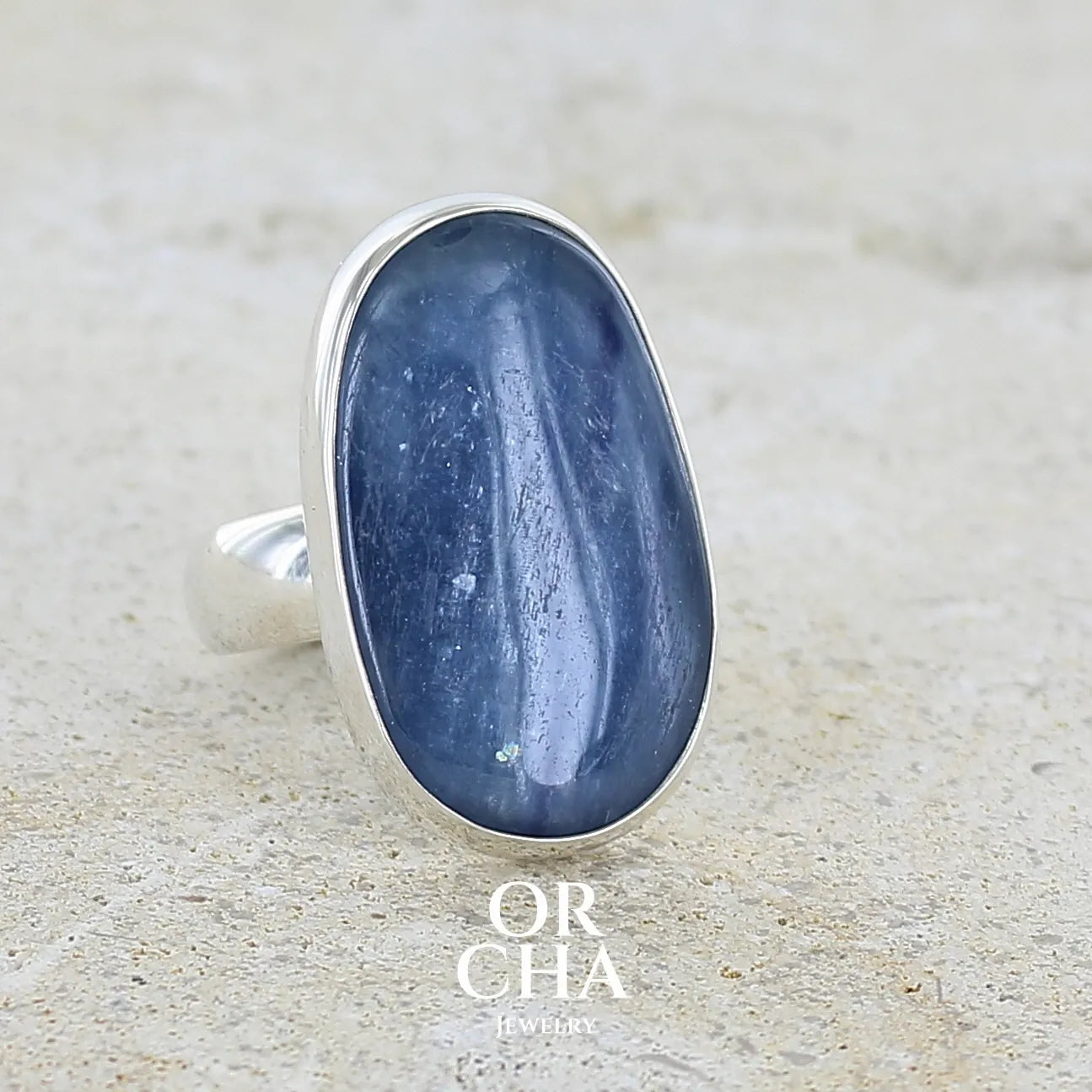 Profil droit d'une bague pour femme en argent massif sertie d'un cabochon de cyanite de couleur bleu jean nacré. Pierre translucide à inclusions de forme ovale arrondie. Bijou unique réalisée en taille 58,5 par Orchajewelry