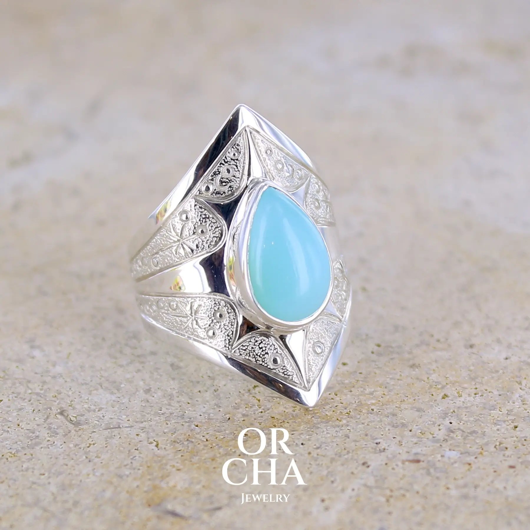 Profil droit d'une bague pour femme en argent massif sculptées d'étoiles et autres corps célestes sertie d'une Opale bleue du Pérou. Pierre cabochon en forme de goutte, pierre naturelle de couleur bleu ciel ciel, bleu turquoise. Pierre naturelle de qualité opaque. Taille 51. Bijoux unique, éthique et durable présenté dans un coffret de notre marque, prêt à offrir. Livraison offerte, certificat d'authenticité, service client.
