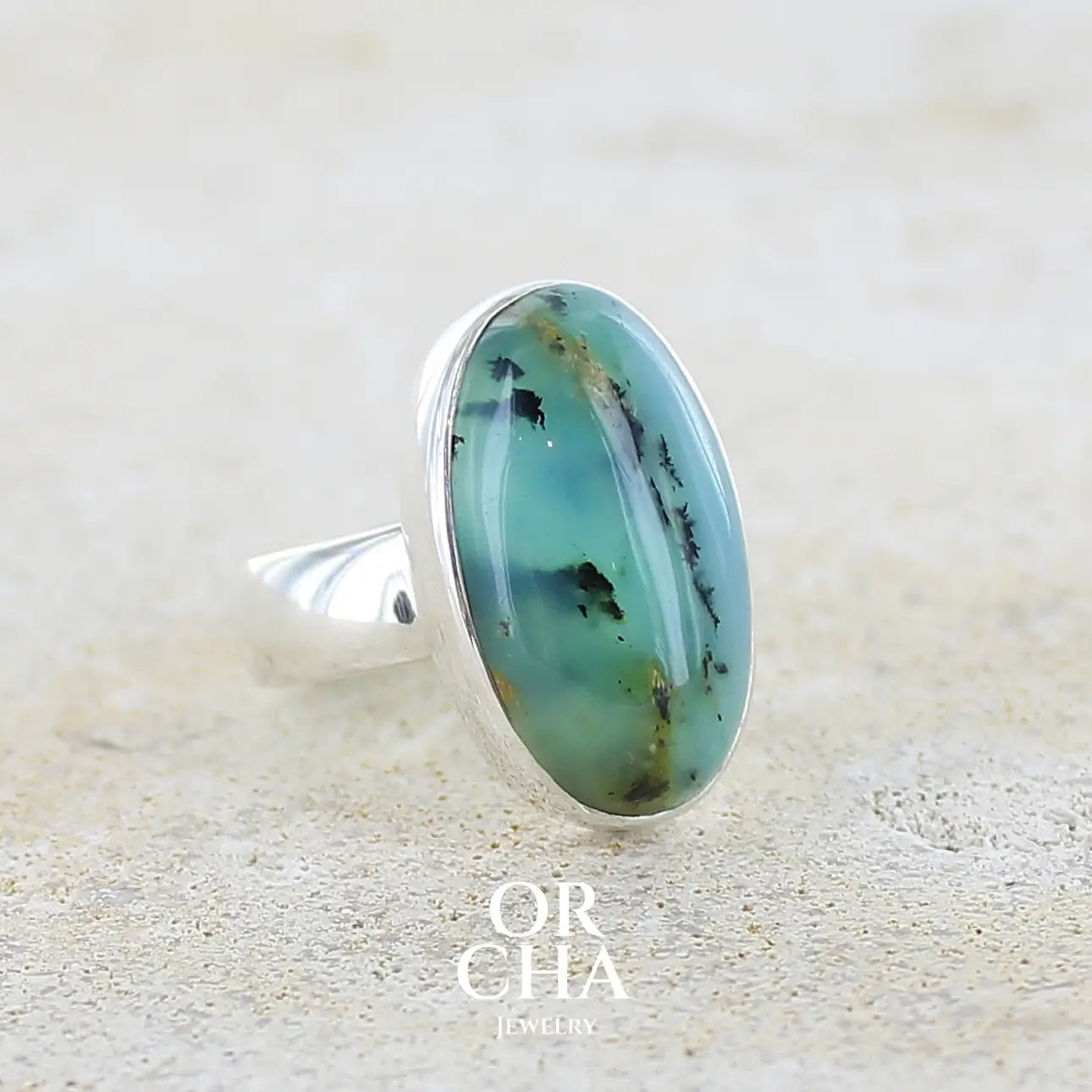 Profil droit d'une bague en argent massif, sertie d'un cabochon ovale d'opale bleue du Pérou de couleur bleu foncé à inclusions de dendrites paysages noires et de roche mère jaune. Pierre naturelle opaque et translucide. Bijoux unique réalisé en taille 52 par Orcha jewelry