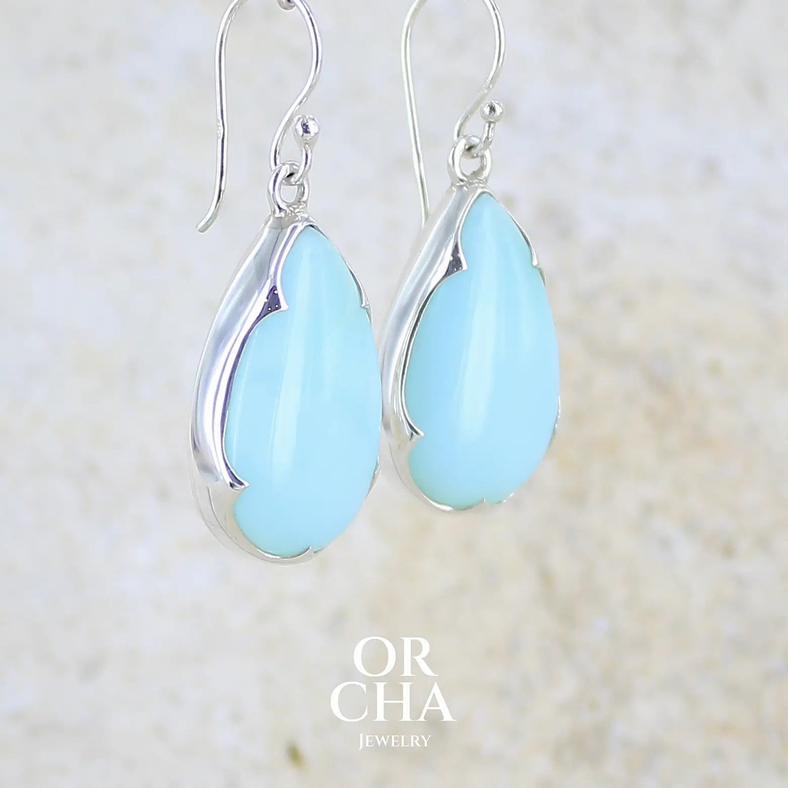 profil droit boucles d'oreilles pendantes en argent massif serties d'opale bleue du Pérou. Pierres cabochon taillée en goutte de qualité opaque. Pierre naturelle de couleur bleu ciel. Bijoux unique, éthique et durable présenté dans un coffret de notre marque, prêt à offrir. Livraison offerte, certificat d'authenticité, service client.