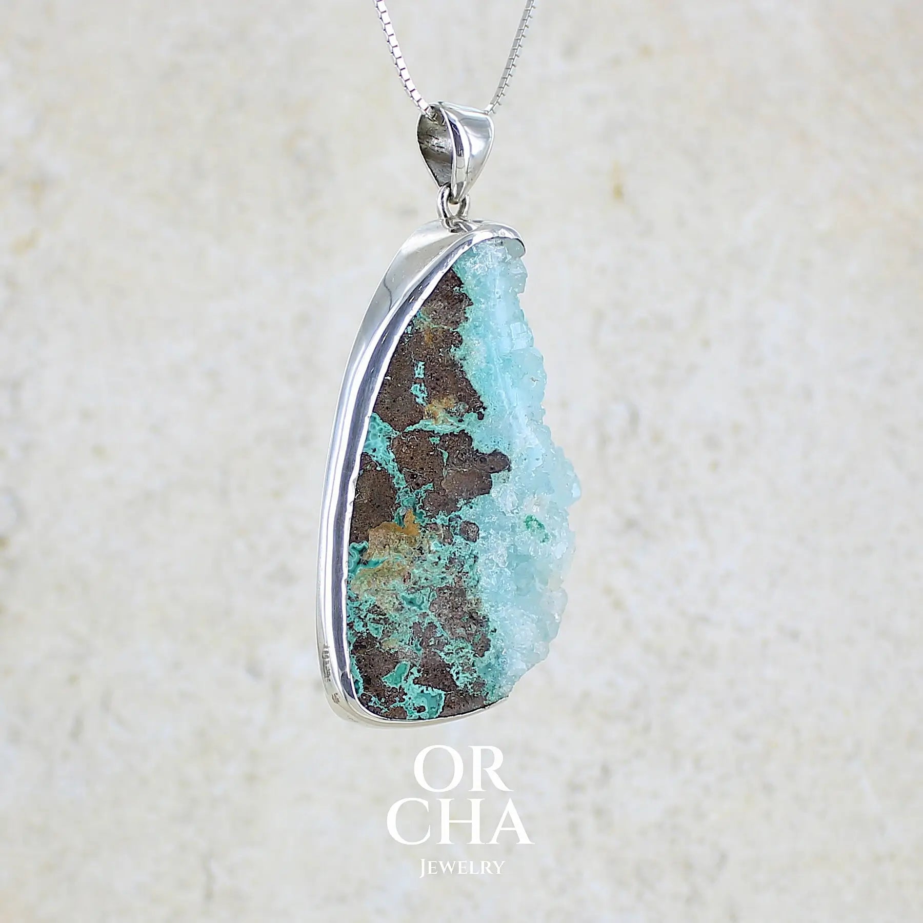 profil droit d'un pendentif en argent massif serti d'un magnifique gemsilica druze: chrysocolle silicifiée recouverte de fins cristaux de quartz scintillant. Pierre de qualité opaque brute en forme de goutte. Pierre naturelle originaire du Mexique de couleur bleue ciel turquoise claire.