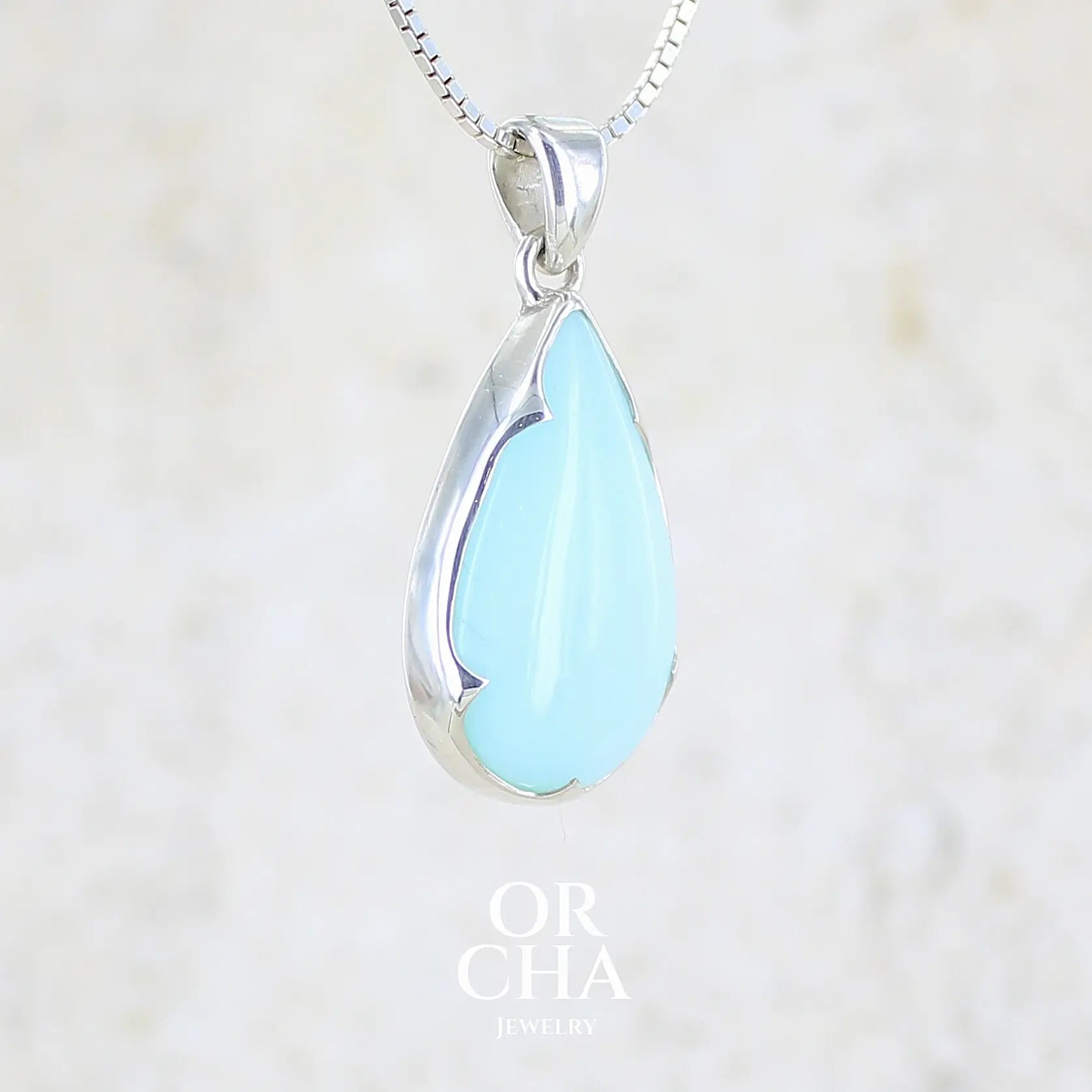 profil droit d'une photo d'un pendentif pour femme en argent massif, sertie d'un cabochon d'opale bleue du Pérou de couleur bleu ciel clair. Pierre en forme de goutte. Pierre opaque. Bijoux unique, éthique et durable présenté dans un coffret de notre marque, prêt à offrir. Livraison offerte, certificat d'authenticité, service client.