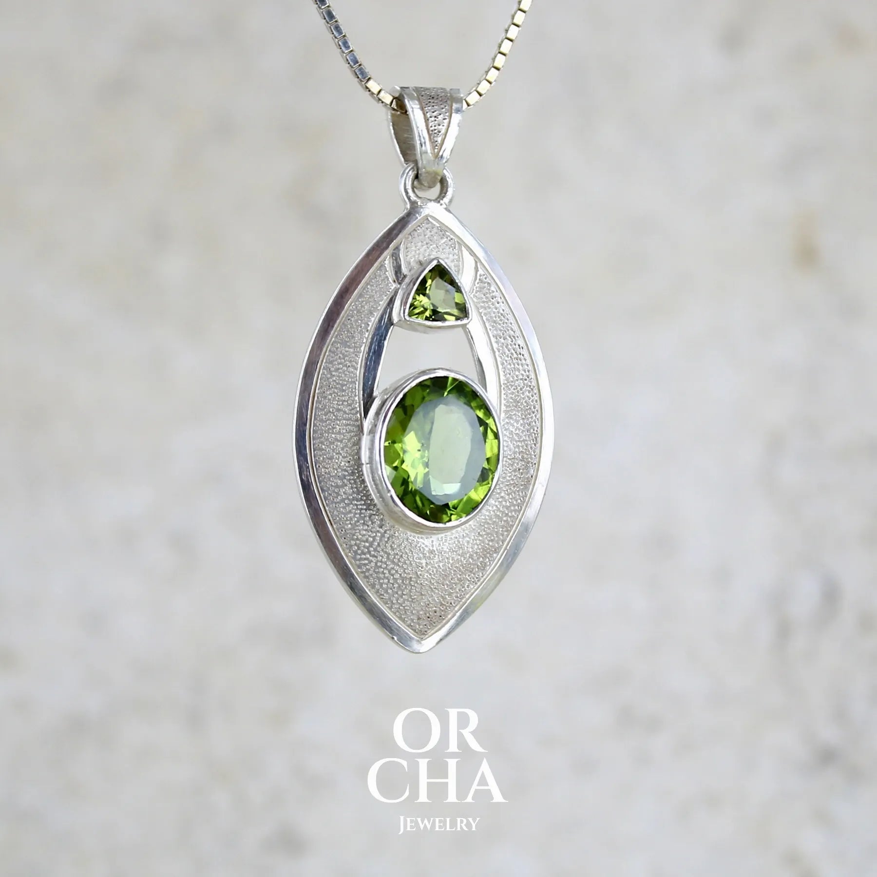 profil droit d'un pendentif pour femme en argent massif serti d'un péridot de couleur vert olive doré intense. Pierre taillée, de forme ovale, transparente propre à l'oeil. Bijou unique réalisé par Orchajewelry
