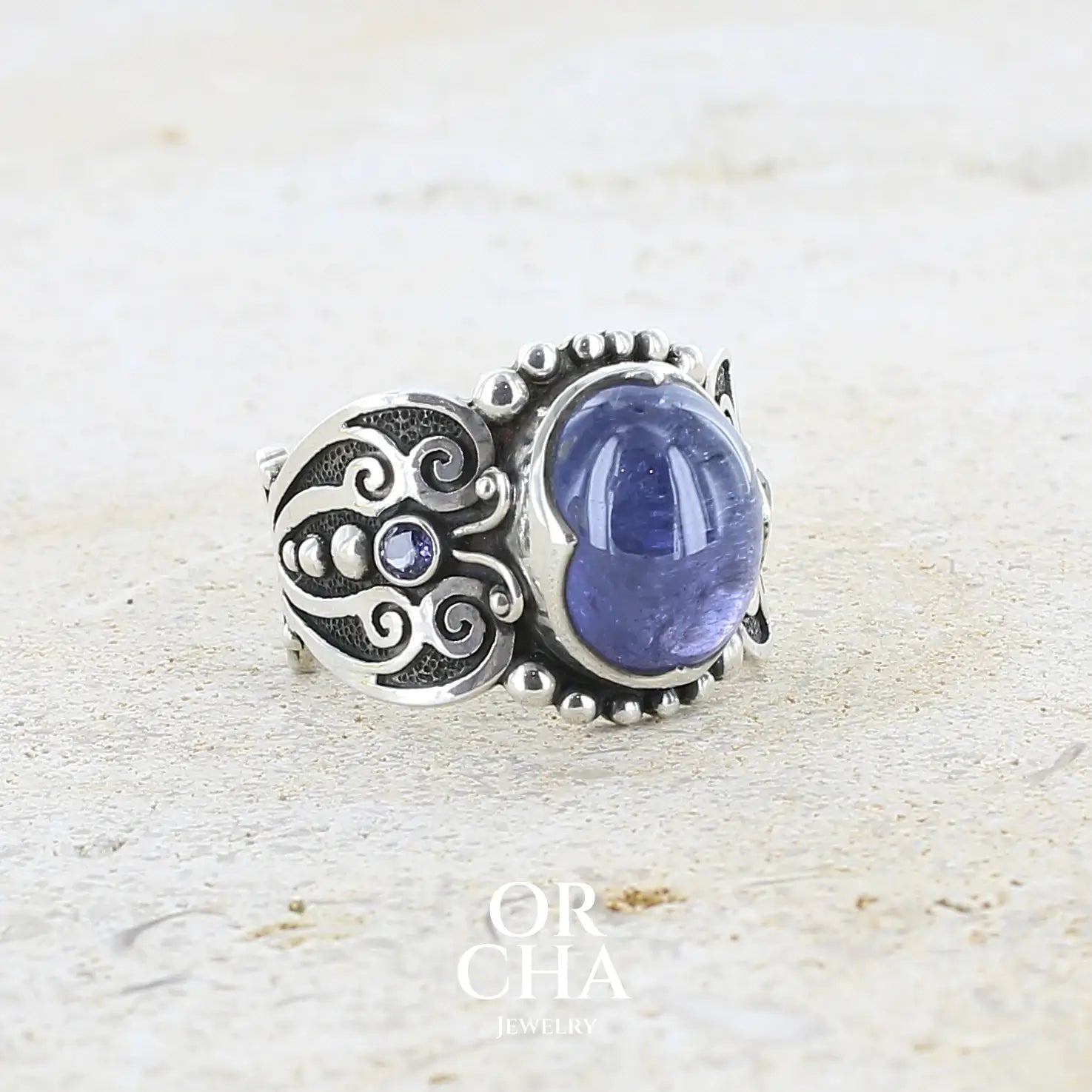 profile droit d'une bague en argent massif sculptées d'entrelacs de style celtique qui illustrent des papillons, sertie d'une Tanzanite. Pierre cabochon de forme ovale, de couleur bleu lavande foncé, de qualité transparente avec inclusions. Taille 56. Bijoux unique, éthique et durable présenté dans un coffret de notre marque, prêt à offrir. Livraison offerte, certificat d'authenticité, service client.
