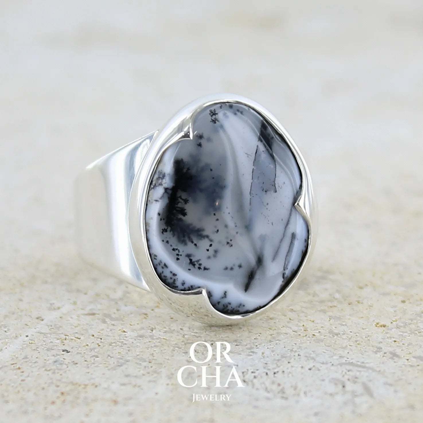 Profil gauche d'une bague pour femme en argent massif sertie d'un cabochon ovale d'agate dendritique de couleur blanc pur et noir. Pierre opaque translucide à inclusions paysages de dendrites de manganèse noires contrastées. Bijou unique réalisée en taille 54 par Orchajewelry