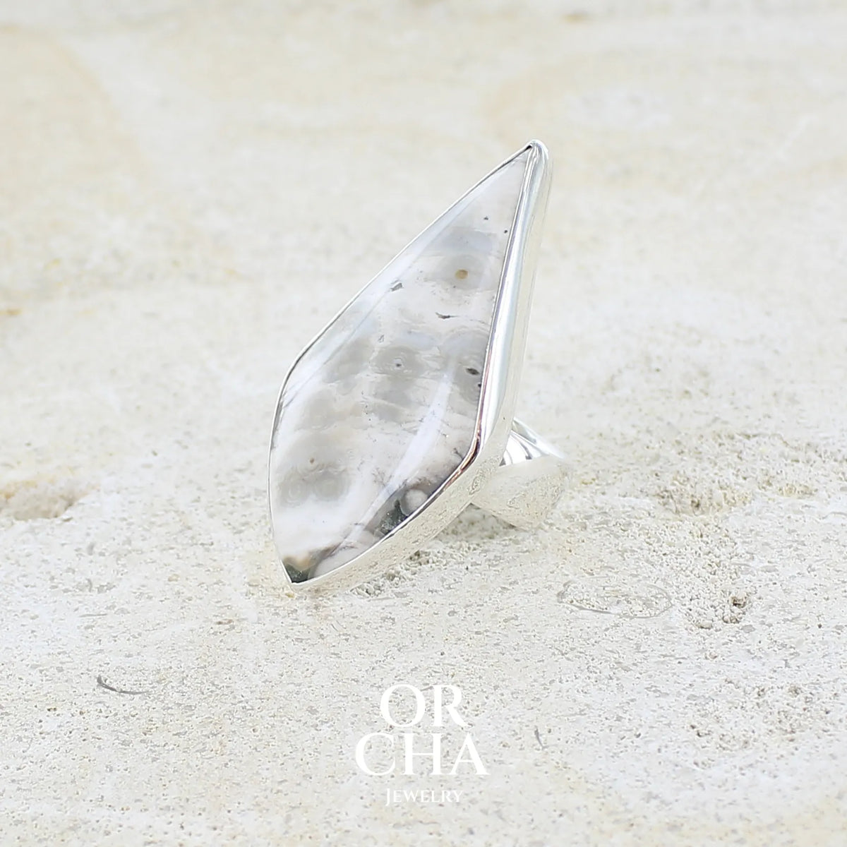 Profil gauche d'une grande bague pour femme en argent massif sertie d'un cabochon de jaspe orbiculaire de couleur crème, kaki et gris. Pierre naturelle de qualité opaque taillée en forme de losange, Bijou unique réalise en taille 56 par Orcha Jewelry