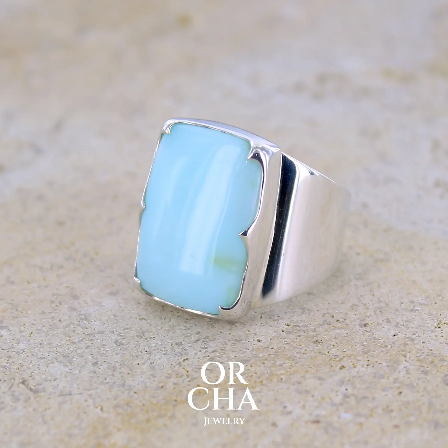 profil gauche d'une bague pour femme en argent massif sculptées d'étoiles et autres corps célestes sertie d'une Opale bleue du Pérou. Pierre cabochon en forme de rectangle, pierre naturelle de couleur bleu ciel ciel, bleu turquoise. Pierre naturelle de qualité opaque. Taille 58. Bijoux unique, éthique et durable présenté dans un coffret de notre marque, prêt à offrir. Livraison offerte, certificat d'authenticité, service client.