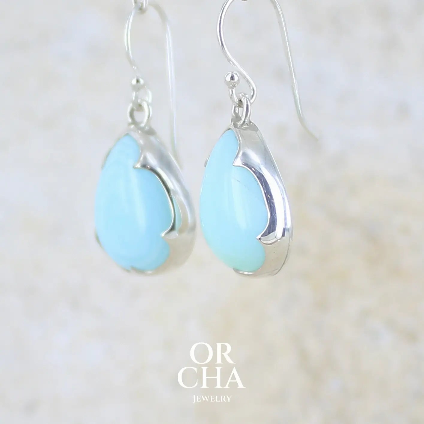 profil gauche boucles d'oreilles pendantes en argent massif serties d'opale bleue du Pérou. Pierres cabochon taillée en goutte de qualité opaque. Pierre naturelle de couleur bleu ciel. Bijoux unique, éthique et durable présenté dans un coffret de notre marque, prêt à offrir. Livraison offerte, certificat d'authenticité, service client.
