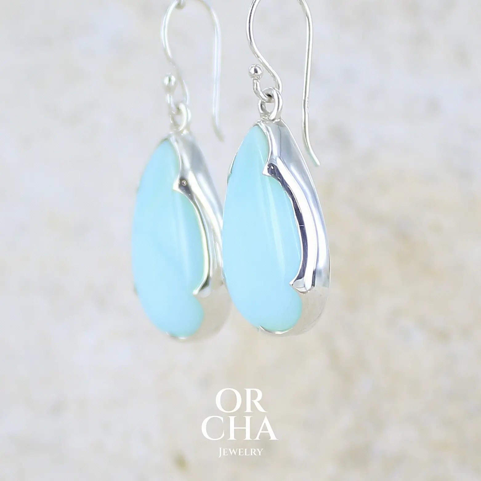 profil gauche boucles d'oreilles pendantes en argent massif serties d'opale bleue du Pérou. Pierres cabochon taillée en goutte de qualité opaque. Pierre naturelle de couleur bleu ciel. Bijoux unique, éthique et durable présenté dans un coffret de notre marque, prêt à offrir. Livraison offerte, certificat d'authenticité, service client.