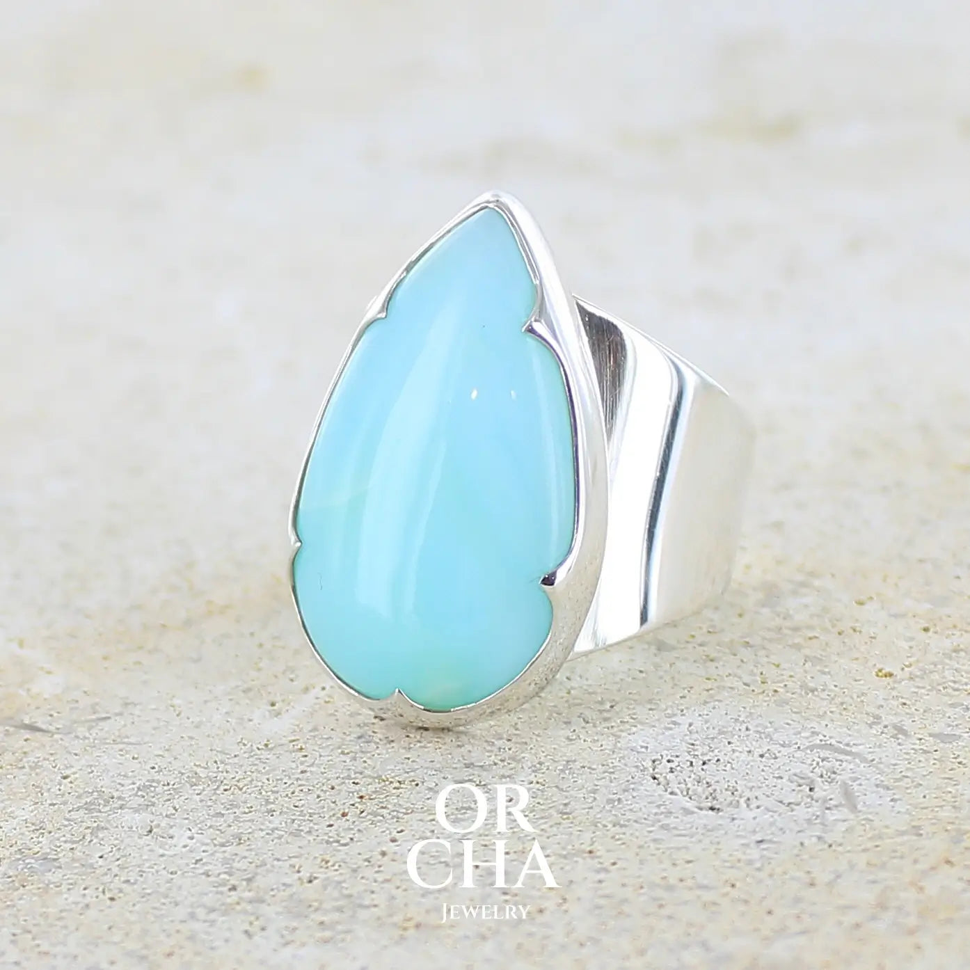 profil gauche d'une grande Bague pour femme en argent massif, sertie d'un cabochon d'opale bleue du Pérou de couleur bleu ciel. Pierre taillée en forme de goutte de qualité opaque. Bijou unique réalisé en taille 60 FR.