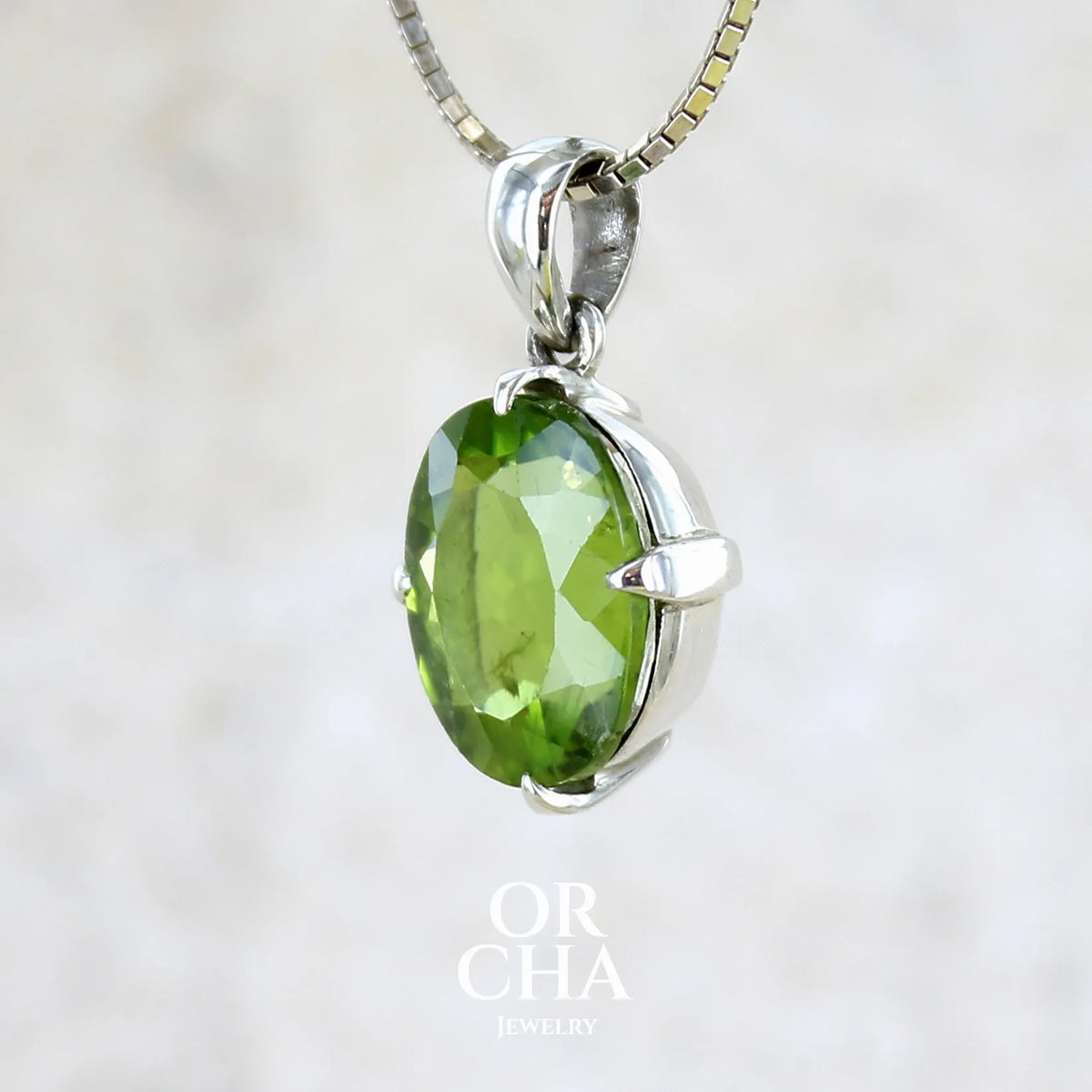 profil gauche d'un pendentif pour femme en argent massif serti d'un Péridot de couleur vert olive doré profond et intense . Pierre taillée transparente présentant des inclusions, de forme ovale. Bijoux unique par Orchajewelry