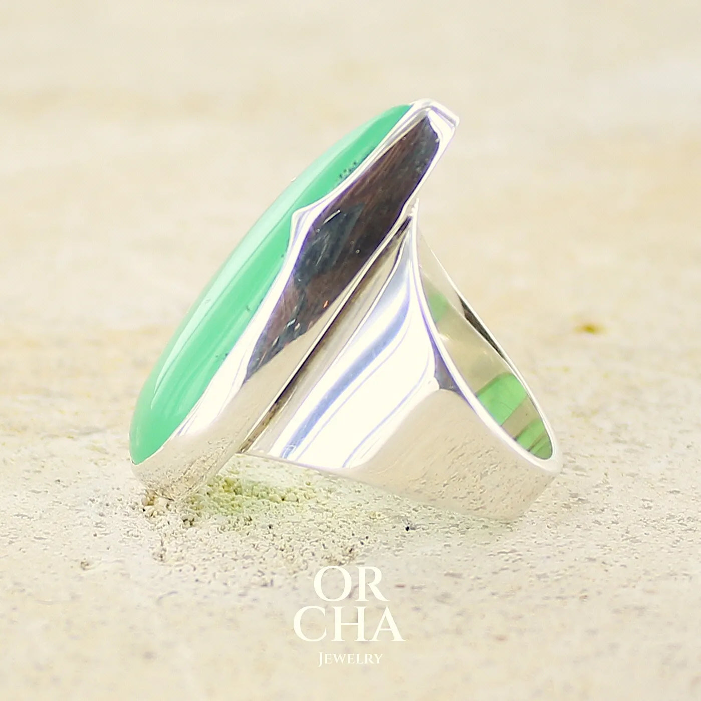 Profil d'une Grande Bague pour femme en argent massif, sertie d'un cabochon de chrysoprase. Pierre naturelle de couleur verte taillée en forme de goutte de qualité translucide. Bijoux unique réalisé en taille 54 par Orchajewelry