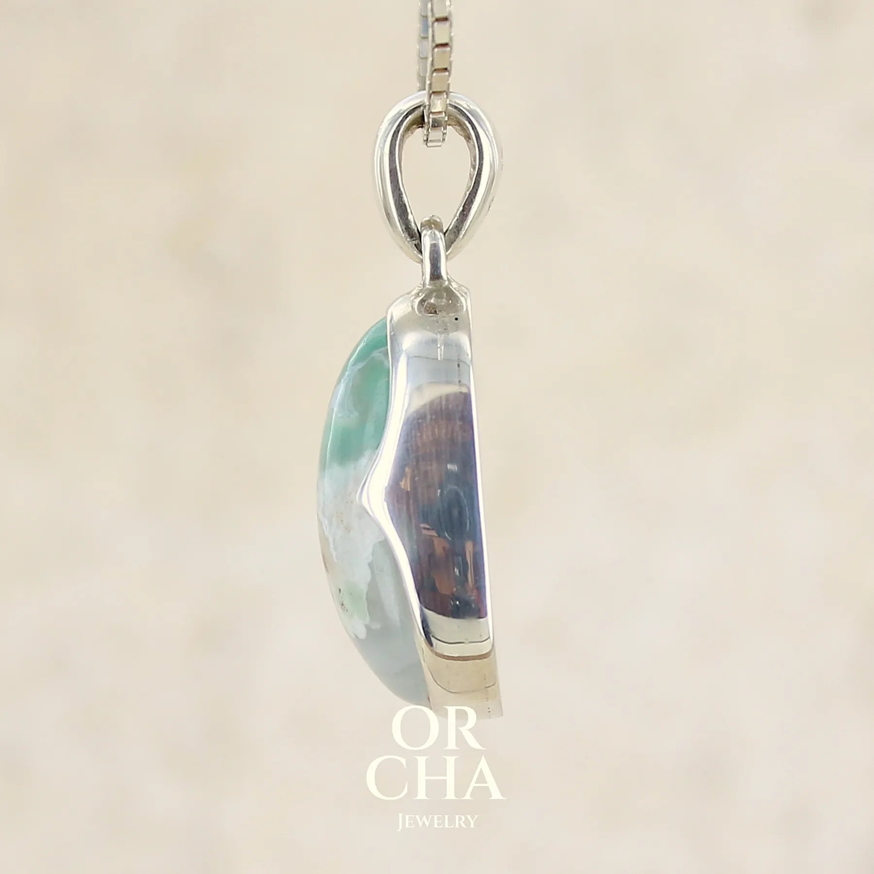 profil d'un pendentif ovale en argent massif, serti d'un cabochon de calcédoine de couleur blanche verte. Pierre de qualité translucide comportant des inclusions paysages blanches. Bijoux unique par Orcha Jewelry
