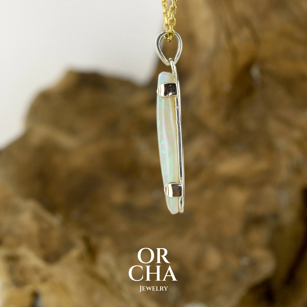 Profil d'un pendentif pour femme en or jaune massif 18k serti d'une opale cristal aux feux étoilés multicolores à dominantes vert et jaune. Cabochon de 1 carat taille en forme de goutte de qualité transparente. Opale australienne de Mintabie. Bijou unique réalisé par Orchajewelry