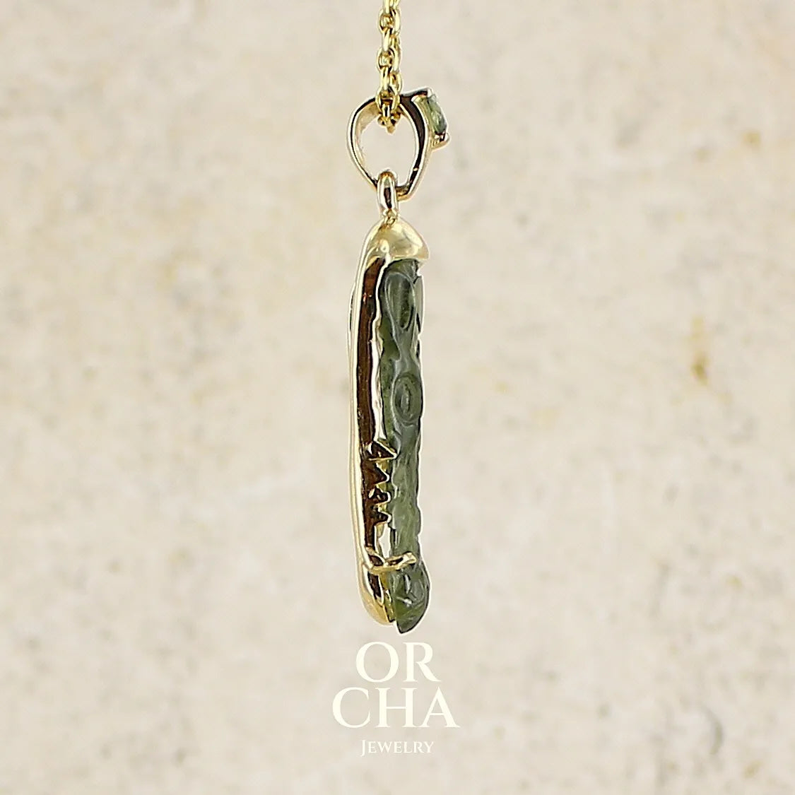 profil d'un pendentif pour homme en or 18k serti d'une moldavite sculptée en tête de crocodile. Pierre naturelle de couleur verte kaki translucide. Bijoux unique par Orcha jewelry