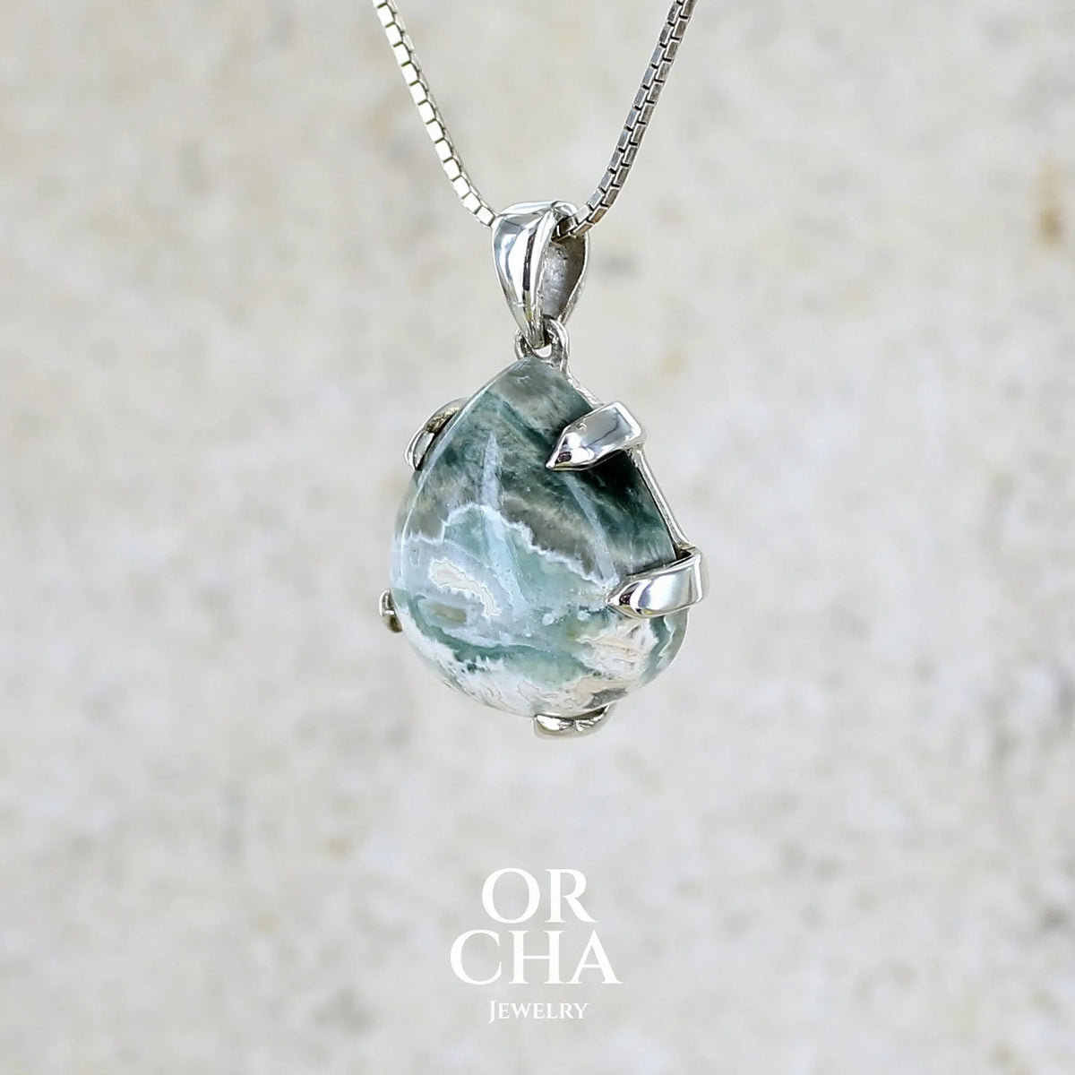 profil gauche d'un pendentif pour femme en argent massif sertie d'un cabochon de jaspe océan de couleur nuancée de kaki et crème. Pierre opaque taillée en forme de goutte. Bijou unique par Orchajewelry
